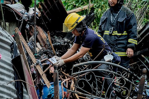 Firefighters check on what remains of the house in Batimana Compound at Barangay Marulas, Valenzuela City which caught on fire following an explosion.