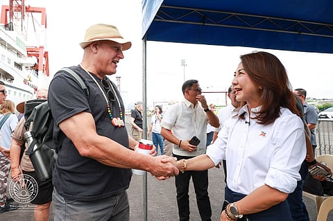 Tourism Secretary Christina Garcia Frasco (right) welcomes a male international tourist who alighted the Villa Vie Odyssey cruise vessel to roam around the province after docking in Cebu International Port for its call on Sunday.