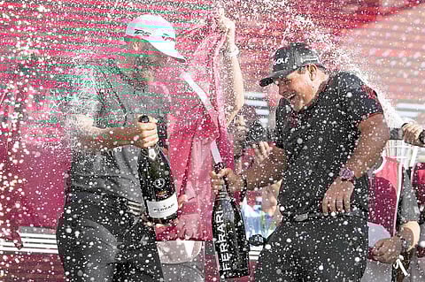 Team captain Dustin Johnson of 4 Aces GC and Patrick Reed celebrate on the podium after the team championship stroke-play round of the LIV Golf Invitational — Miami at Trump National Doral Miami in 2022 in Doral, Florida.