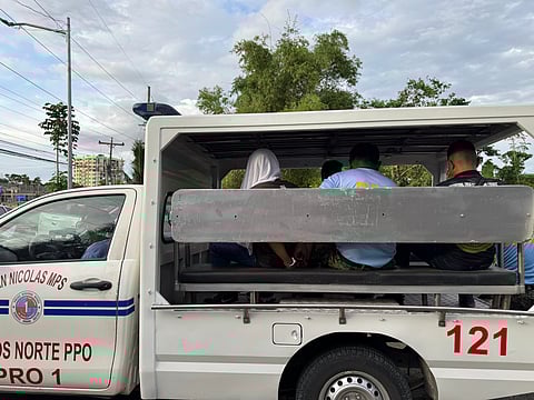 Police officers escort a male suspect, his head covered with a white towel, aboard a patrol vehicle of the San Nicolas Municipal Police Station on Tuesday afternoon, October 21, 2025. Authorities identified him as Police Corporal Mark Jirreh Requiso, the alleged gunman in the Madamba–Bonilla double slay in San Nicolas, Ilocos Norte. Requiso, assigned to the Tourist Police Unit, is facing double murder and frustrated murder charges and has been committed to the Ilocos Norte Provincial Jail.