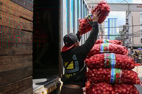 Harvests of promise A worker heaves sacks of imported onions at the Santo Cristo market in Manila, their sheen glinting under the afternoon light.