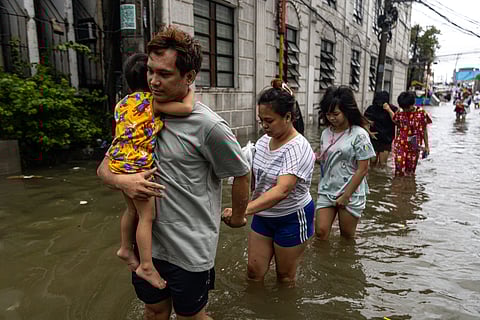 People wade through chest-deep floodwater in Barangay Navotas East, Navotas City on Monday, 10 November 2025, after the Malabon-Navotas Navigational Gate overflowed Sunday night amid high tide and storm surges driven by Super Typhoon Uwan.
