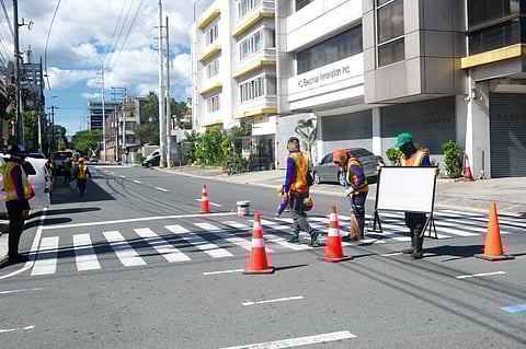 Workers from the Department of Public Works and Highways repaint a pedestrian crossing along Quezon Avenue. Various concerned agencies are already gearing up to enhance pedestrian safety along major thoroughfares in the metro.