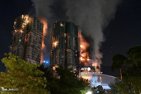 Thick smoke and flames rise during a major fire at the Wang Fuk Court residential estate in Hong Kong's Tai Po district on November 26, 2025. At least 13 people have died as a result of a raging fire that tore through several high-rise blocks in a Hong Kong residential estate on November 26, a government official said.
