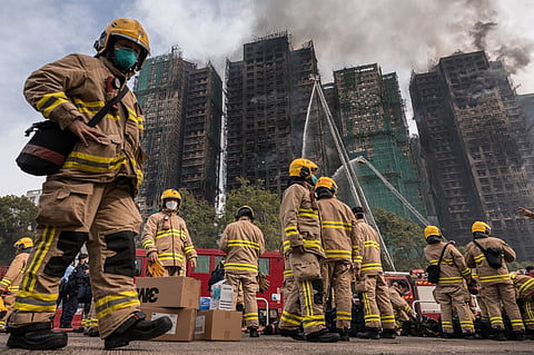 Firemen get ready after a major fire swept through several apartment blocks at the Wang Fuk Court residential estate in Hong Kong's Tai Po district on November 27, 2025. Hong Kong firefighters were scouring a still-burning apartment complex for hundreds of missing people on November 27, a day after the blaze tore through the high-rises, killing at least 44.