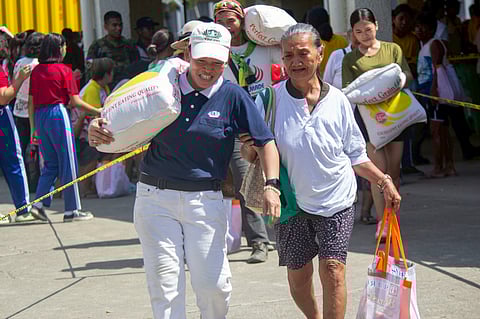 A TZU Chi volunteer helps carry a 25-kilo rice received by a resident during the relief goods distribution of the humanitarian organization at the Opao gymnasium in Mandaue, Cebu on 28 November 2025.
