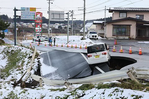 A vehicle rests on the edge of a collapsed road in Tohoku town in Aomori Prefecture following a 7.5 magnitude earthquake off northern Japan. A big quake off northern Japan left at least 30 injured, authorities said on 9 December, damaging roads and leaving thousands without power in freezing temperatures.