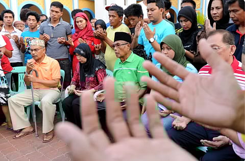 Self-proclaimed Sultan of Sulu Jamalul Kiram, centre, and his supporters pray at a mosque in Manila on March 6, 2013 for his followers battling Malaysian forces in Sabah