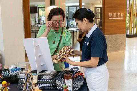 TZU Chi Foundation Philippines deputy CEO Woon Ng (right, above) shows a Christmas tree made from strips of upcycled denim to a bazaar shopper. Father and son (top) mix cupcake ingredients during the baking workshop at the Tzu Chi Great Love Preschool Philippines.