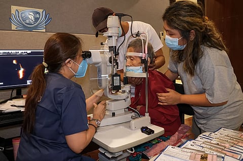 MARIAN (right) and husband JC (background) watch their mom’s eyes examined at the Tzu Chi Eye Center.