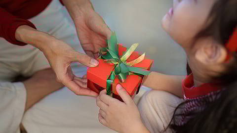 A child receives a Christmas gift from a godparent during the holiday season.
