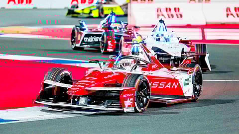 FORMULA E action sees Nissan cars running in close pack racing during a night event as the team balances performance with emissions tracking efforts.