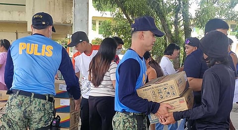 PERSONNEL from the Philippine National Police assist in the distribution of Family Food Packs at the Tagaytay Elementary School in Barangay Bariw, Camalig, Albay to evacuees from Barangay Anoling.