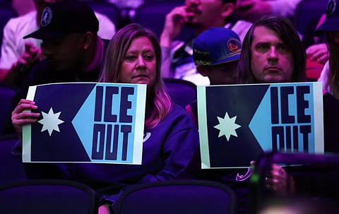 FANS hold signs to protest the presence of federal immigration agents in Minneapolis prior to the start of the third quarter of an NBA game between the Golden State Warriors and Minnesota Timberwolves