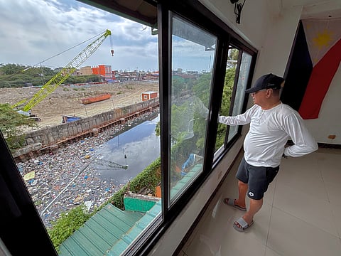 CHAIRMAN Norberto Manalad Jr. surveys the clogged waters of Estero de Vitas from his office at Barangay 151, highlighting the ongoing garbage buildup and irregular booster pump operations.