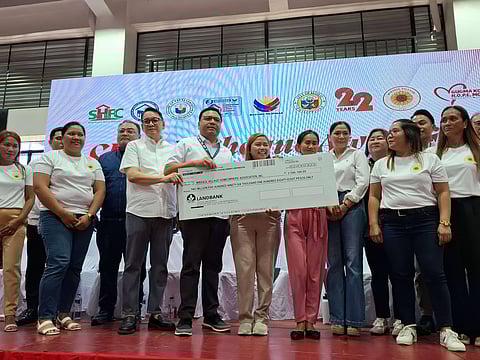 SOCIAL Housing Finance Corporation president and CEO Federico Laxa (left) and Department of Human Settlements and Urban Development Secretary Jose Ramon Aliling hand a mock check worth P2.6 million to Mirasol Village Homeowners’ Association president April Rose Segumalian and another co-officer.