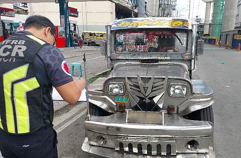 A Land Transportation Franchising and Regulatory Board officer issuing a violation to a passenger jeepney during the department's surprise inspection in Quezon City last Tuesday.