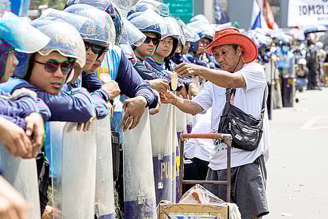 WHILE the country commemorates the 40th EDSA People Power anniversary, an ice cream vendor continues to make a living as he sells his merchandise to policemen barricading a part of EDSA in Mandaluyong City on Wednesday.