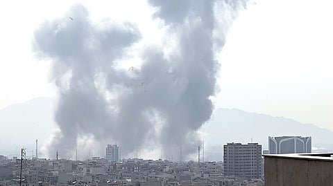 GRAY smoke rises above Tehran following a reported explosion on 28 February. (Inset) A video grab taken from UGC images posted on social media shows perspective from a street in the city. Two loud blasts were heard in the morning by AFP journalists, and two plumes of thick smoke were seen over the center and east of the Iranian capital. Israel’s defence ministry announced it had launched a ‘preemptive strike’ on Iran as sirens sounded in Jerusalem and people across the country received phone alerts about an ‘extremely serious’ threat. (Left) A smartphone shows US President Donald Trump making a statement regarding combat operations on Iran, ostensibly ‘to defend the American people by eliminating imminent threats from the Iranian regime.’