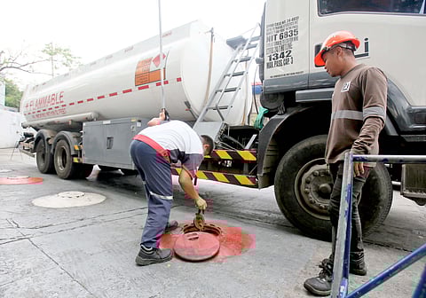 GAS attendants check fuel levels at a station along East Avenue in Quezon City on Tuesday after oil companies raised prices amid ongoing tensions in the Middle East.