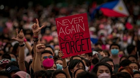 KAKAMPINK supporters hold up a ‘Never Again, Never Forget’ placard at a 2022 campaign rally for then-presidential candidate Leni Robredo, a slogan now at the heart of the debate over a rumored Marcos-opposition alliance that labor leader Luke Espiritu has branded a ‘kiss of death’ for the anti-Duterte camp.