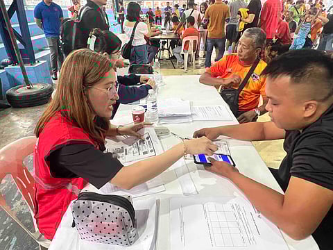 A personnel of the Department of Social Welfare and Development scrutinizes the requirements of a tricycle driver during distribution of cash assistance on Tuesday in Sta. Mesa, Manila.