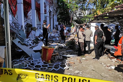 Police officers look at a building of the North Sumatra's National Sports Committee of Indonesia (KONI) damaged following a severe 7.4-magnitude offshore quake in Manado, North Sulawesi on April 2, 2026.