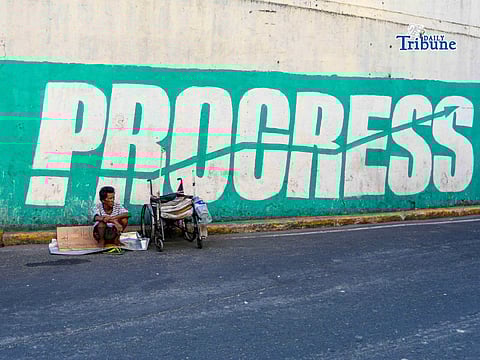 A disabled man is seen juxtaposed against a graffiti from a clothing brand reading “PROGRESS” in Quiapo, Manila last 1 April.