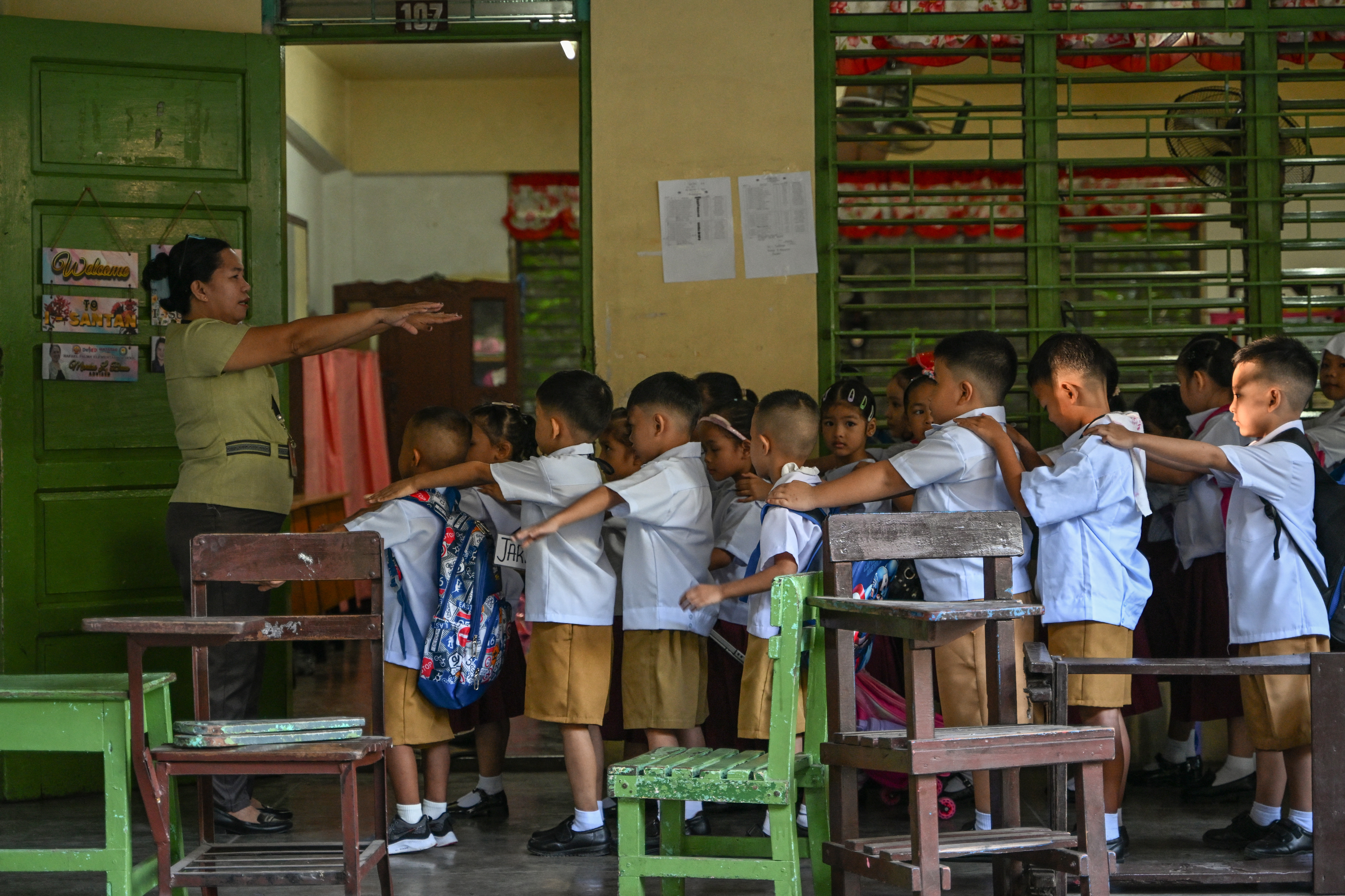 Knowledge sacrifices A teacher guides her pupils in elementary school in Manila, where education presses on despite the punishing summer heat.