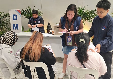PERSONNEL from the Department of Migrant Workers assist the overseas Filipino workers who were recently repatriated from the Middle East.