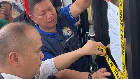 PERSONNEL from the Department of Migrant Workers padlock an unlicensed agency in Manila on Monday. The firm was shut down for allegedly defrauding aspiring overseas Filipino workers with false promises of high-paying jobs abroad.