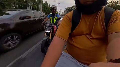 A SCREENGRAB shows a Quezon City Police District police staff sergeant attempting to push a civilian motorcycle rider off the road on C5 in Pasig City. The victim, Vincent Cayanes, captured the Tuesday morning incident on camera, which shows the officer causing the crash before fleeing the scene.