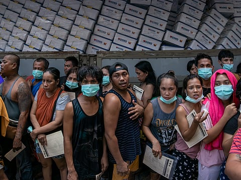 DISPLACED residents of the Parola Compound queue for hot meals at the Delpan Evacuation Center in Manila on Sunday. Thousands of individuals are seeking shelter at the center after a massive fire tore through their coastal neighborhood on Saturday afternoon.