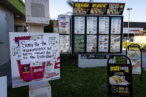 A sign is posted at a fast-food drive-through closed due to an evacuation following a chemical leak from a large storage tank in Garden Grove, California. Authorities said a crack was found in the damaged tank, potentially easing pressure as nearly 50,000 residents were evacuated over fears of an explosion.