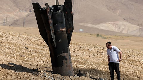 A MAN checks a fallen rocket half-buried in the ground on the outskirts of Jericho on 8 June 2026, following Iranian and Iran-backed Houthi rebel attacks.