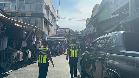 A Batasan police officer raises a placard on Wednesday, 17 June, reminding passersby to remain vigilant and safeguard their personal belongings within Commonwealth Market, Brgy. Commonwealth, Quezon City. (Photo courtesy of Batasan Police Station 6)