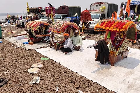 A gathering of palanquins on the banks of the Krishna River