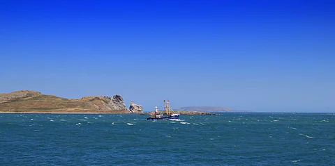 A fishing trawler passing the uninhabited island of Ireland's Eye off Howth Harbour in Dublin Bay, Ireland.