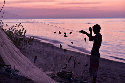 Silhouette of the indonesian fisherman removing fishes from the fishin net, Gİli Meno Island, Indonesia.