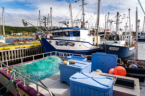 Heart's Content Newfoundland Canada, September 26 2022: Fishing boats moored at a dock with fish nets and storage bins on deck at a maritime community.