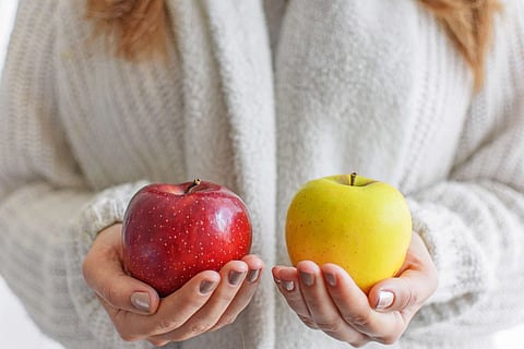 A midsection of a female holding fresh apples