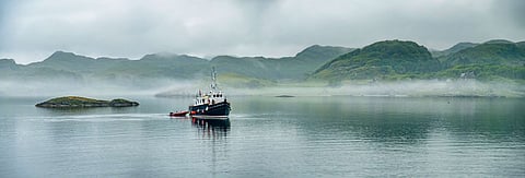 Alone boat driving through in the foggy sea in the Highlands of Scotland