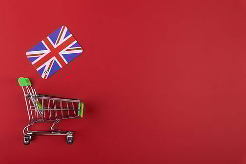 Mini empty supermarket shopping grocery cart, UK flag on red background, concept consumption, import and export, european food delivery service, copy space for text, horizontal, flat lay