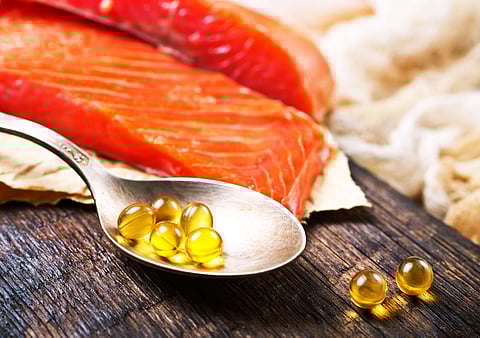 Fish oil capsules with omega 3 on wooden board. Photo by: Adobe Stock.