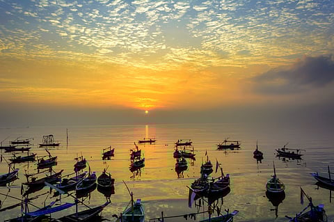 Fishermen boats at sunrise on beach in Surabaya, Indonesia. Photo by: Adobe Stock.