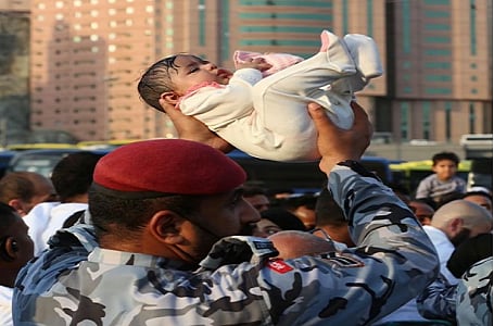 صورة مؤثرة لرجل أمن يحمل طفلا وسط الزحام في الحرم المكي