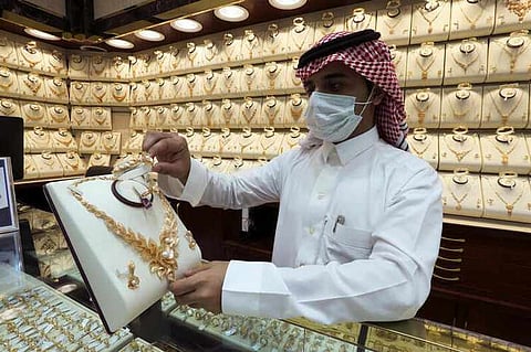 A Saudi jeweller wearing a protective face mask displays a gold necklace to customers at a jewellery store during the holy month of Ramadan, following the outbreak of the coronavirus disease (COVID-19), in Riyadh, Saudi Arabia May 5, 2020. REUTERS/Ahmed Yosri