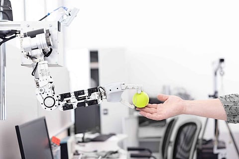 Robotic Hand Holding Service Bell In Plate Against Grey Background