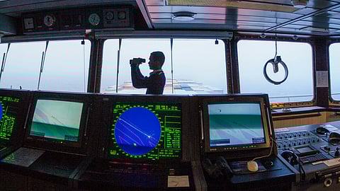 Navigator with binoculars on ship's bridge