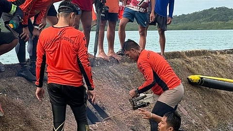 A Philippine Coast Guard rescuer uses a chainsaw to breach the hull of the overturned fishing boat Jobhenz off the Philippines' Cagayan province, September 23, 2025. Seven of the boat's 13-strong crew were killed after it capsized in bad weather brought about by Typhoon Ragasa the day before.